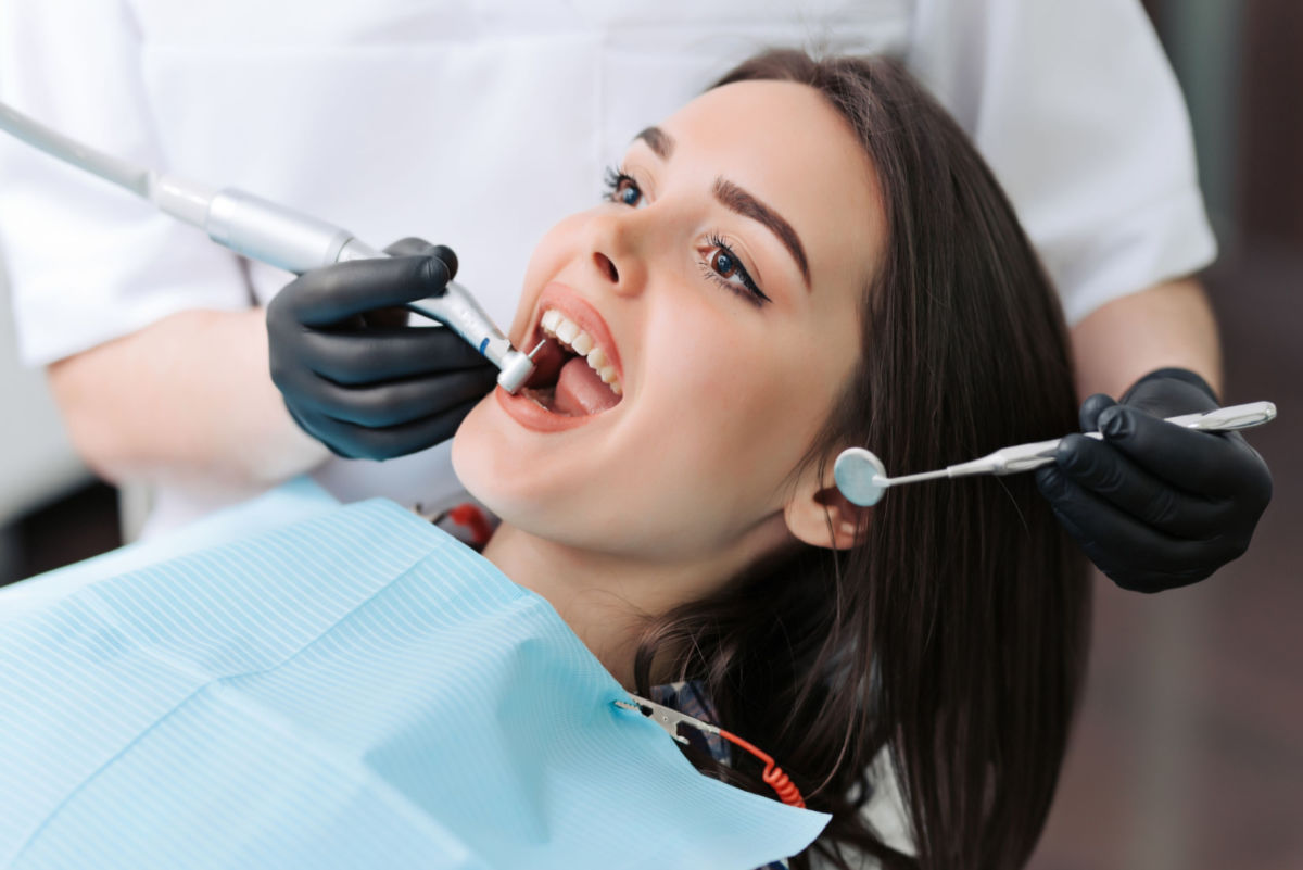 A young woman laying in the dentist’s chair and getting an oral exam